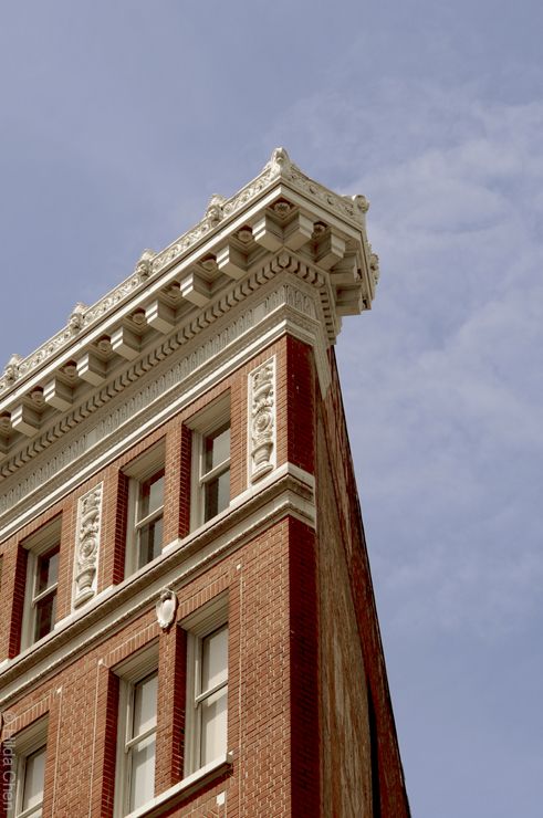 the corner of a building with a clock on it's side and sky in the background