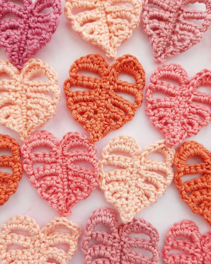 crocheted hearts are arranged in rows on a white surface, with one heart shaped at the center