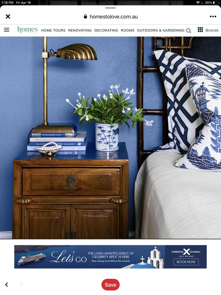 a bed room with blue walls and a wooden night stand next to a nightstand topped with flowers