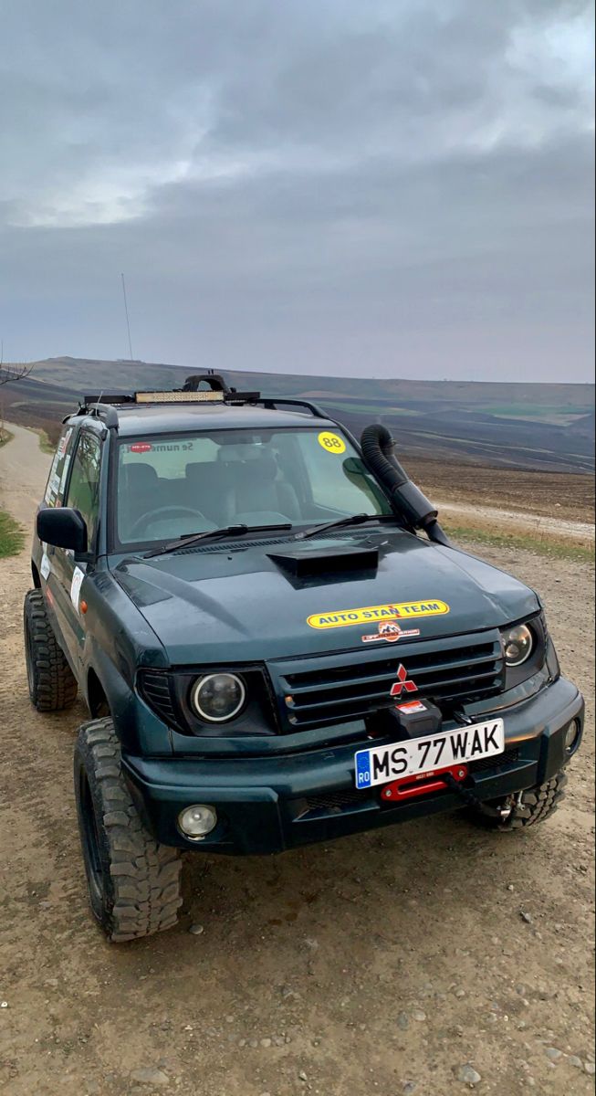 an suv parked on the side of a dirt road