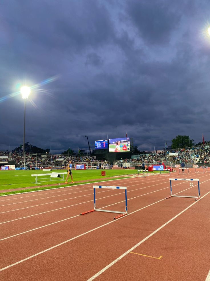 an empty track with the lights on and spectators in the stands