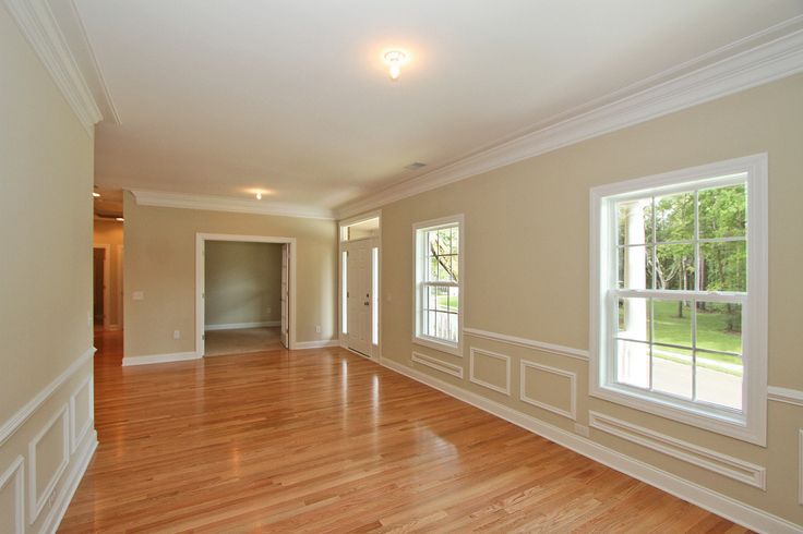 an empty living room with hard wood flooring and white trim on the walls, along with two windows