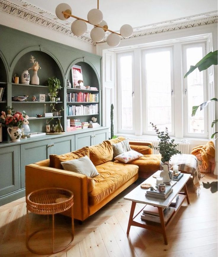 a living room filled with furniture next to a window covered in lots of bookshelves