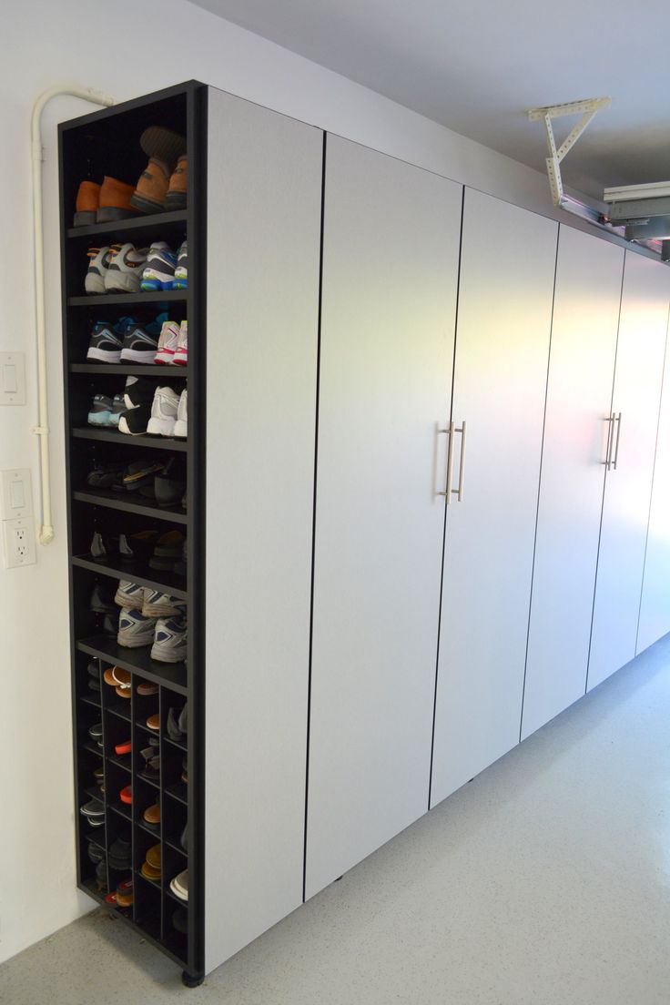 a large closet with several pairs of shoes on the bottom shelf and two doors open