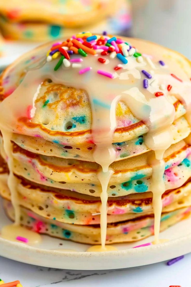 a stack of pancakes covered in icing and sprinkles on a plate