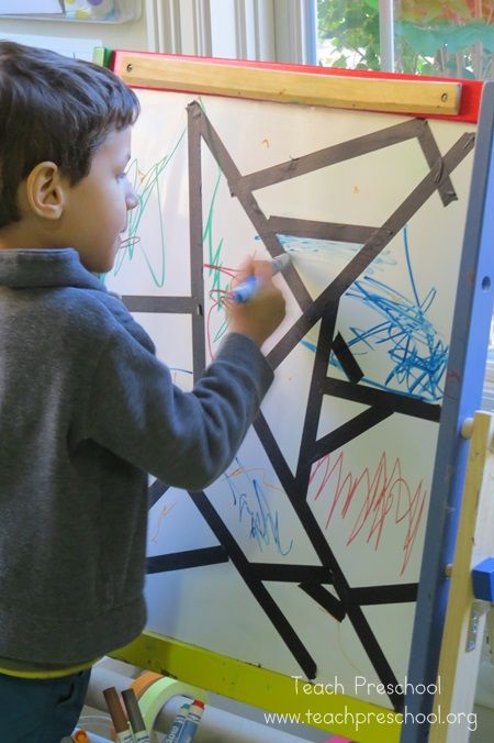 a young boy writing on a white board