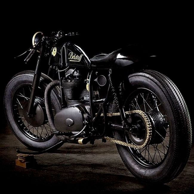 a black motorcycle parked on top of a wooden platform in the dark with no one around it