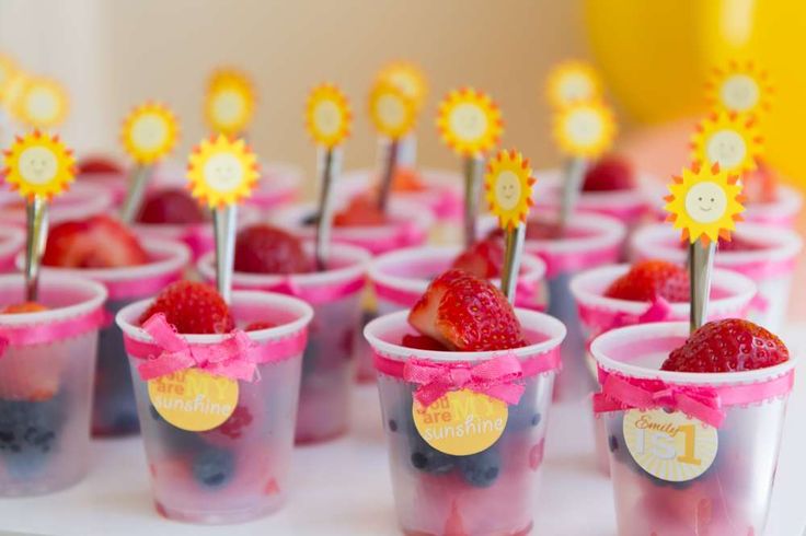 small cups filled with fruit on top of a white cake plate next to yellow plates