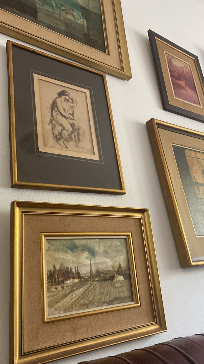 several framed pictures hang on the wall next to a leather couch in a living room