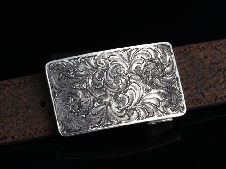 One of our most popular buckles, this understated piece by Comstock Heritage is perfect for those just starting their buckle collections, or for more formal occasions. It’s made from heavy-gauge, hand-engraved Sterling silver, and its rectangular face is adorned with beautiful, delicate scrollwork. This buckle can be paired easily blue jeans or be worn with dressier slacks. Smaller size measures 1 ⅝” x 2 ⅝” and fits all 1 ¼" belt traps Larger version measures 1 ⅞” x 2 ¾" and fits all 1 ½" belt s Antique Engraved Belt Buckles For Formal Wear, Classic Concho Belt Buckles For Formal Wear, Luxury Formal Jewelry With Silver Buckle, Vintage Engraved Belt Buckles For Formal Wear, Western Engraved Belt Buckles For Formal Wear, Vintage Engraved Belt Buckles For Formal Occasions, Western Style Antique Belt Buckle For Formal Wear, Western Style Antique Belt Buckle For Formal Occasion, Formal Engraved Belt Buckles