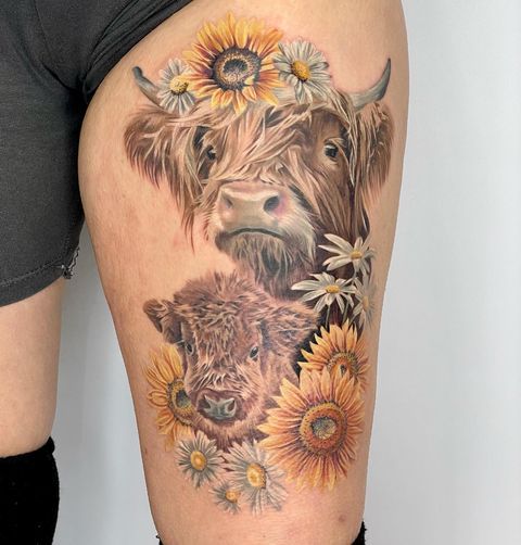 a woman's thigh with an animal and sunflowers tattoo on her leg