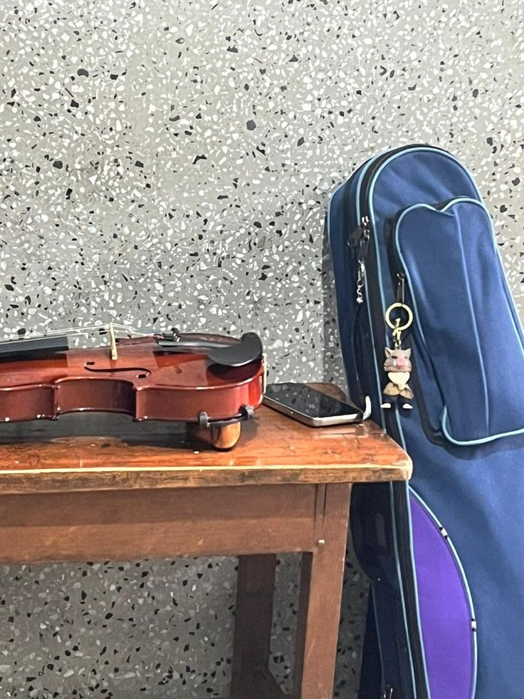 a violin sitting on top of a wooden table next to a blue case and instrument