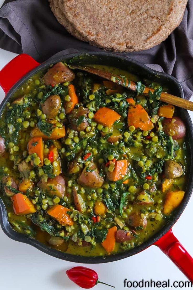 a pan filled with vegetables and meat next to a pita bread on a table