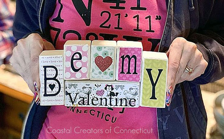 a woman holding blocks that spell out the word be my valentine