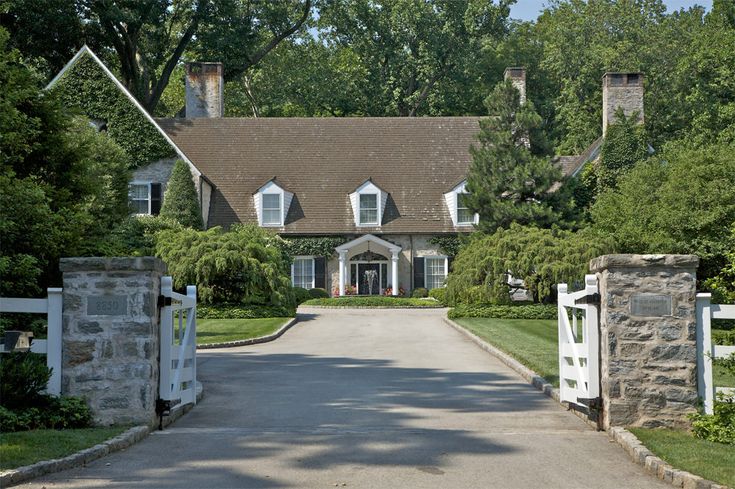 a large house with a driveway leading to the front door and two gates that lead into it