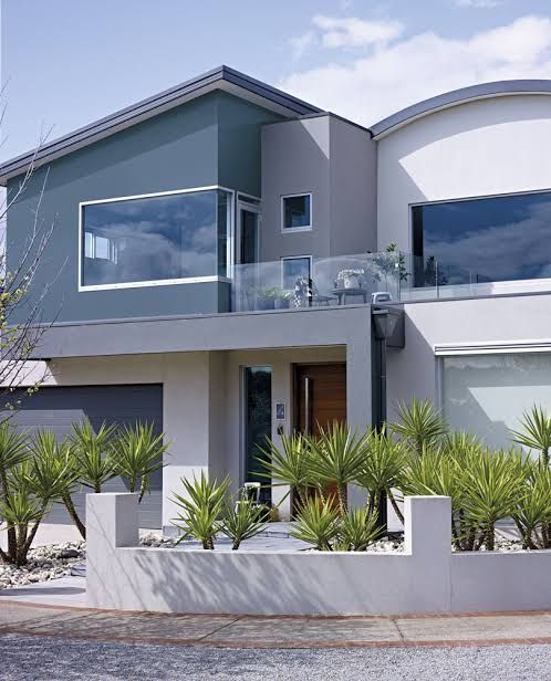 a modern house with plants in the front yard