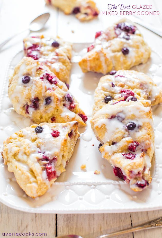 blueberry scones with icing on a white platter next to silverware