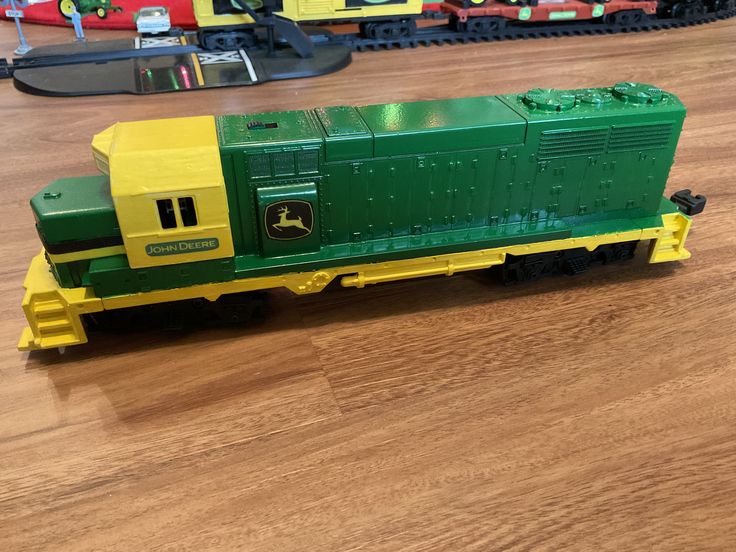 a green and yellow toy train sitting on top of a wooden floor next to other toys