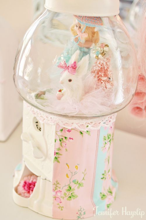 a glass jar filled with toys sitting on top of a white table next to a stuffed animal