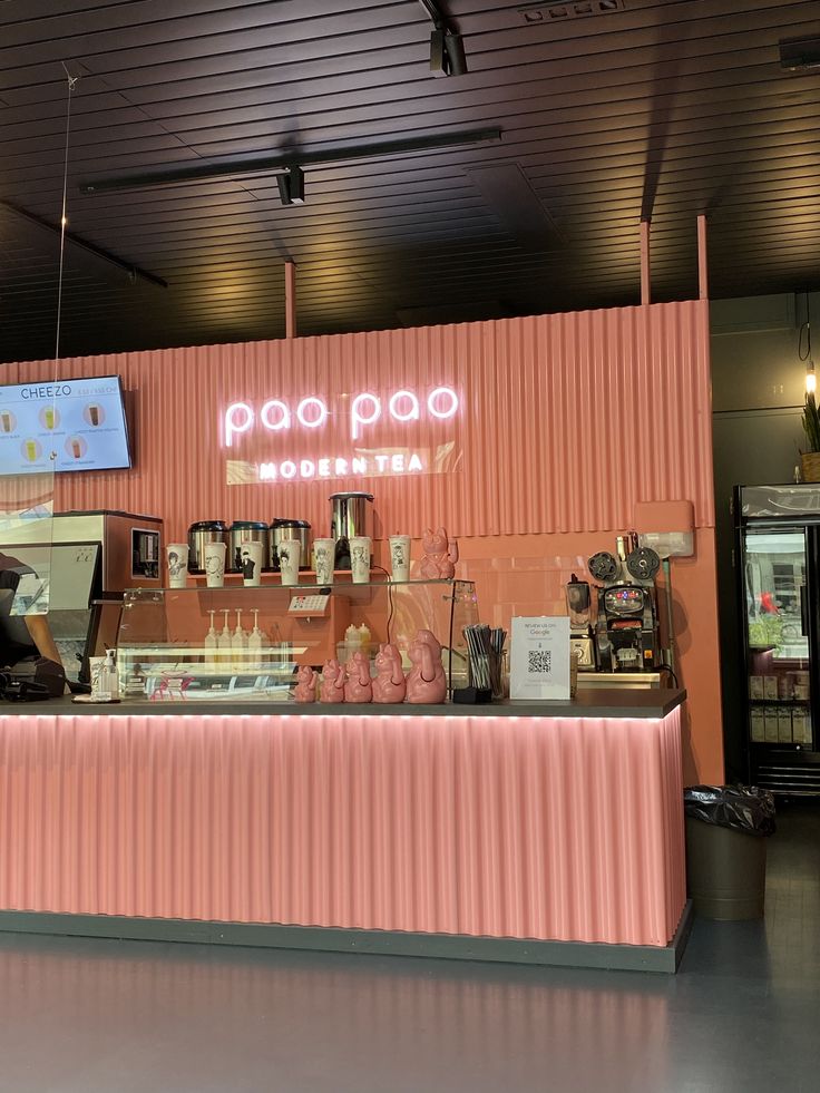 the inside of a restaurant with pink walls and neon signs on the wall above the counter