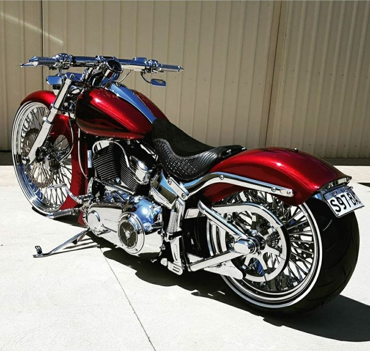 a red and black motorcycle parked on top of a cement floor next to a building