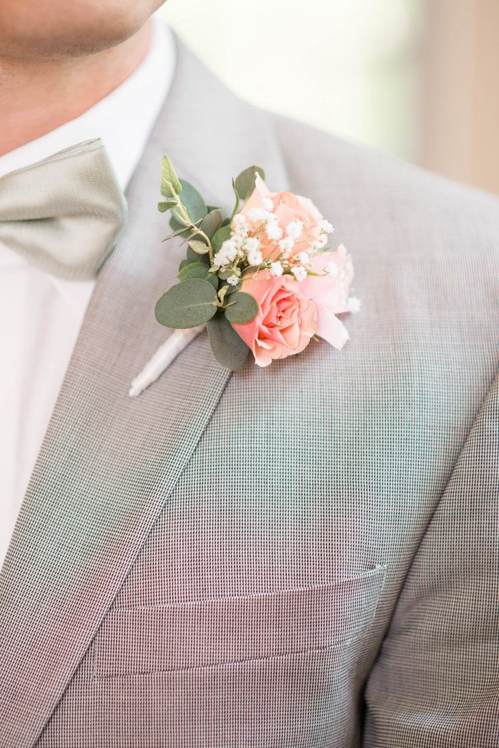 a man in a suit and bow tie holding a boutonniere with flowers on it