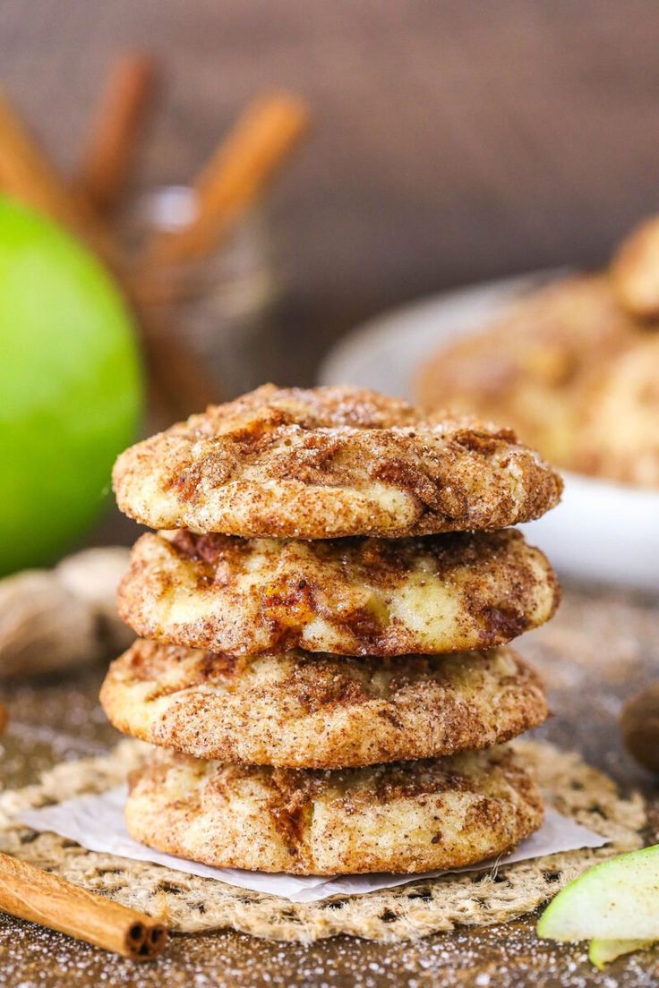 a stack of cookies sitting on top of a table next to an apple and cinnamon stick