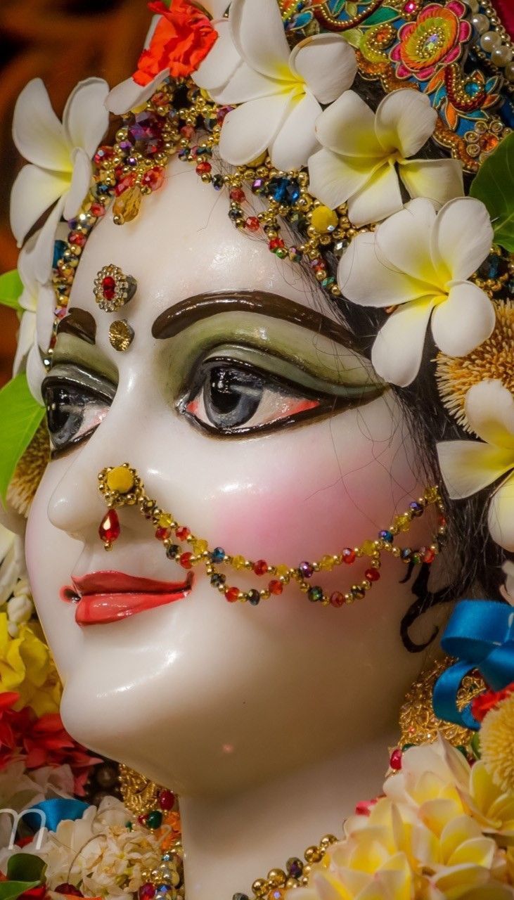 a close up of a mask with flowers on it's head and eyes covered in beads