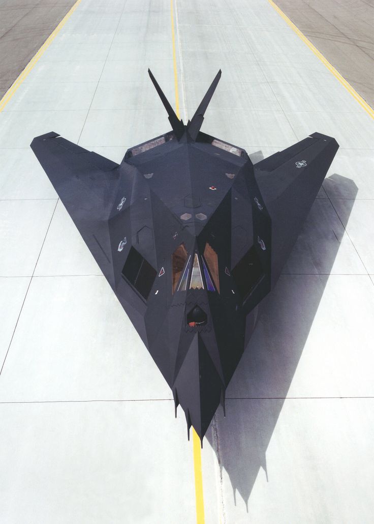 a fighter jet sitting on top of an airport tarmac next to a yellow line