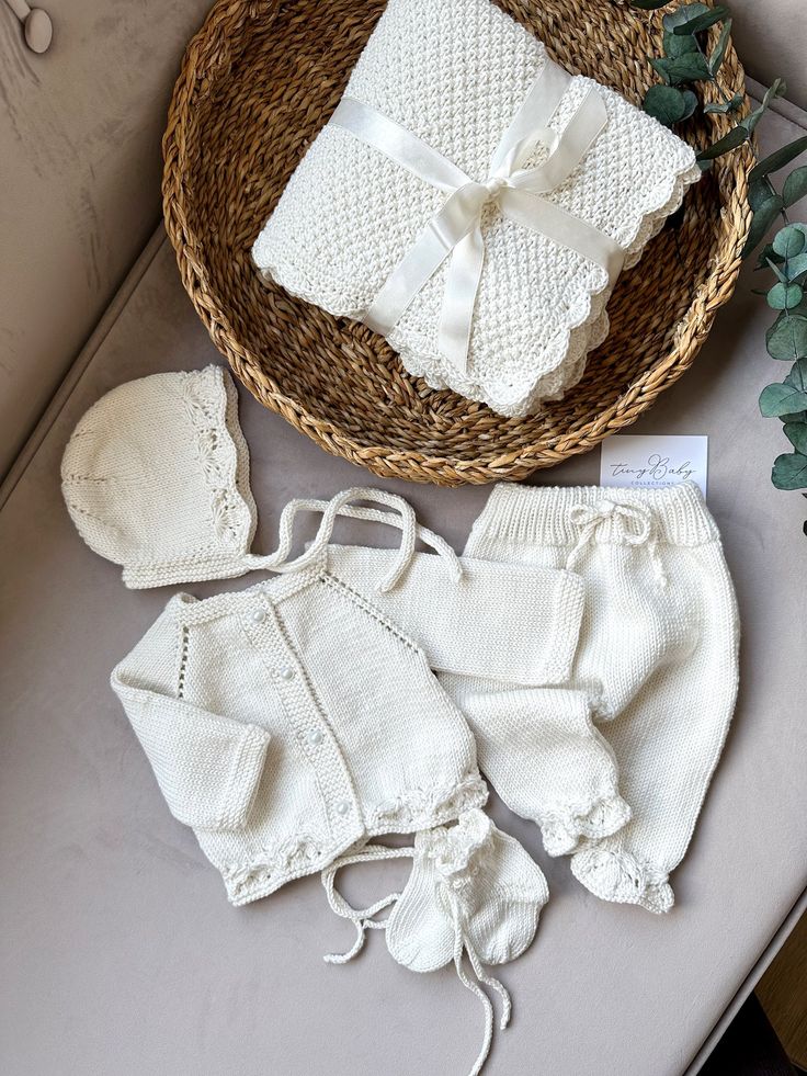 knitted baby clothes and bonnets are sitting on a table next to a basket