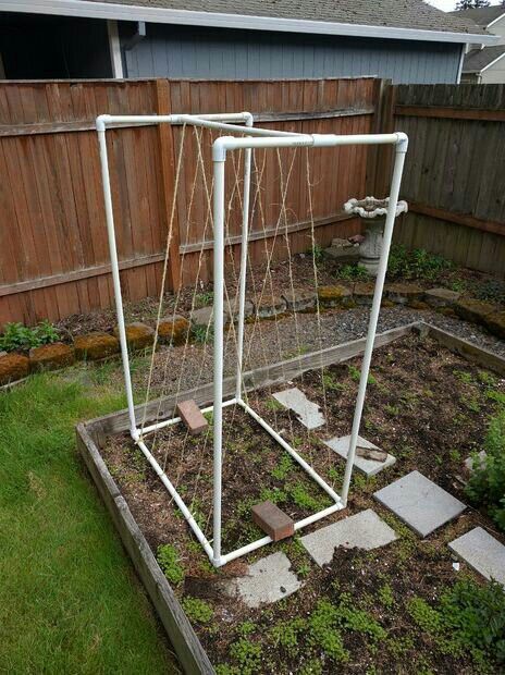 an old swing frame is in the middle of a garden with grass and rocks around it