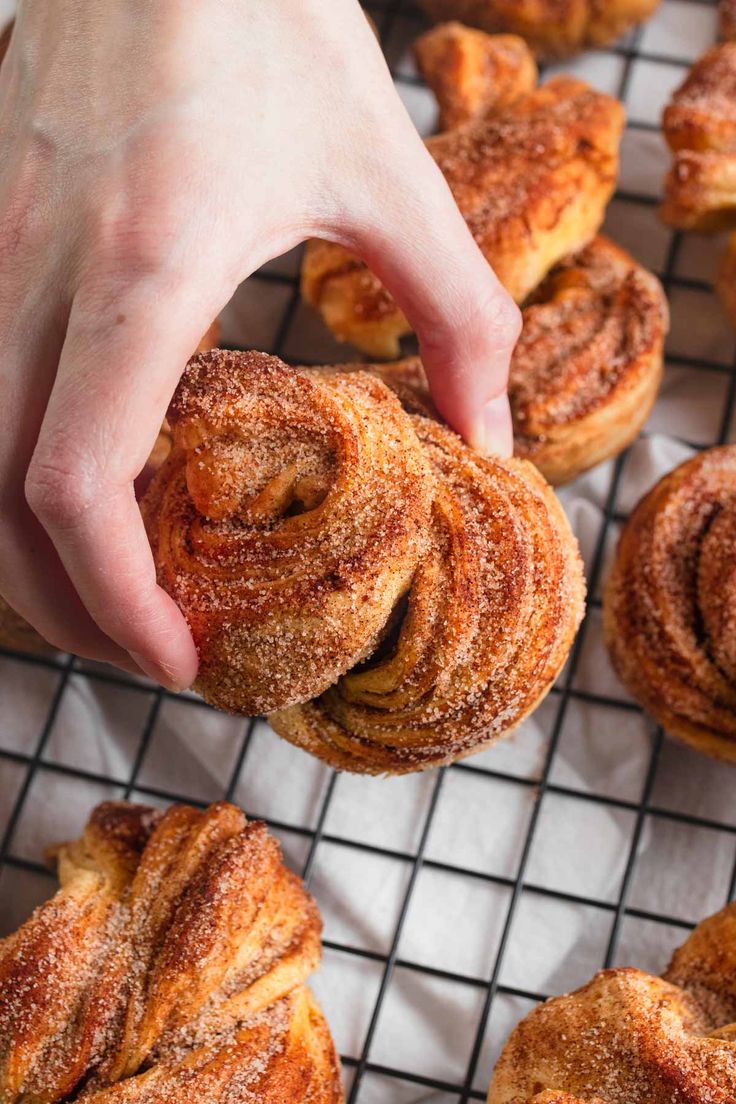 a person is picking up some cinnamon rolls