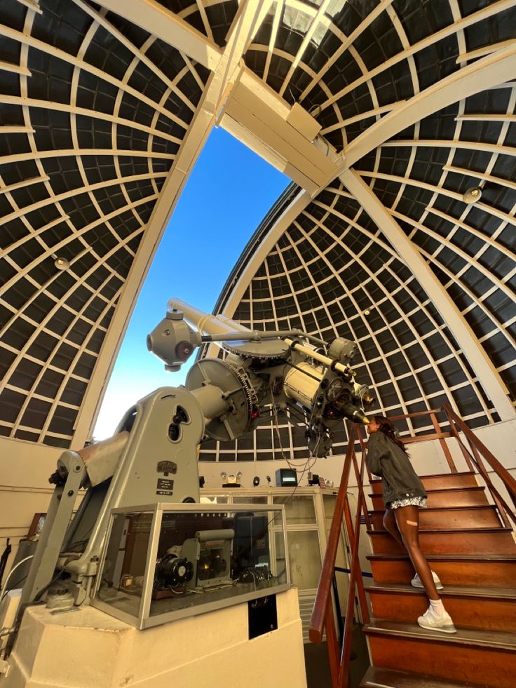 a telescope mounted to the side of a building next to a stair case in front of a skylight