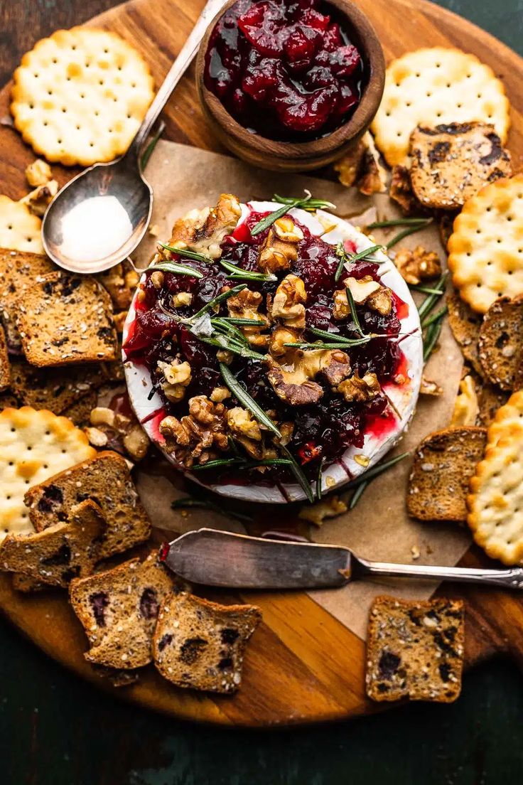 a plate with crackers, cranberry sauce and walnuts on the side