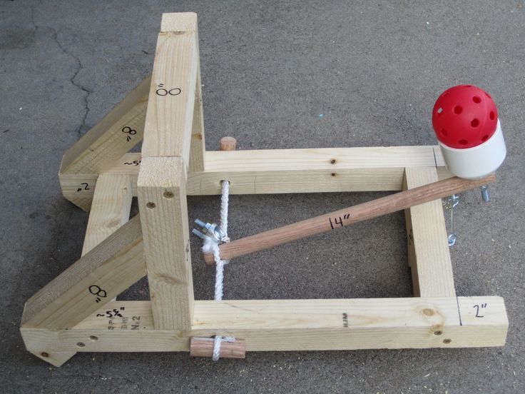 a wooden frame with two hammers and a red ball on the ground next to it