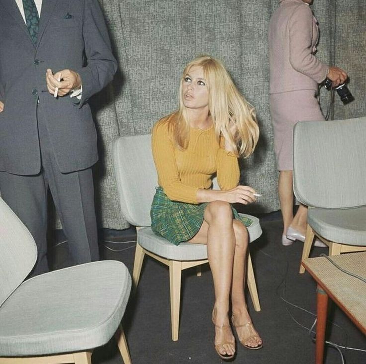 a woman sitting on a chair in front of two men and one woman standing behind her