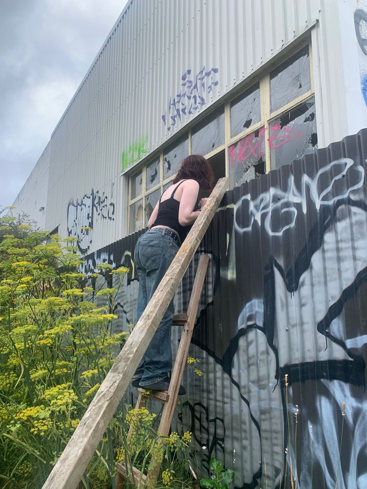 a woman climbing up the side of a building with graffiti on it's walls