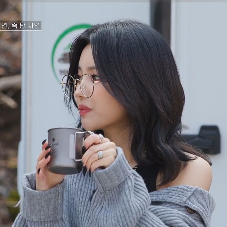 a woman with glasses holding a coffee cup