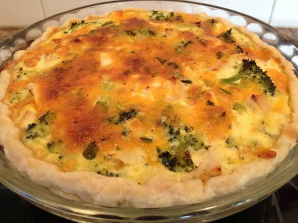 a quiche with cheese and broccoli in a glass dish on the stove