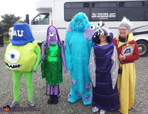 four people dressed in costumes standing next to a bus