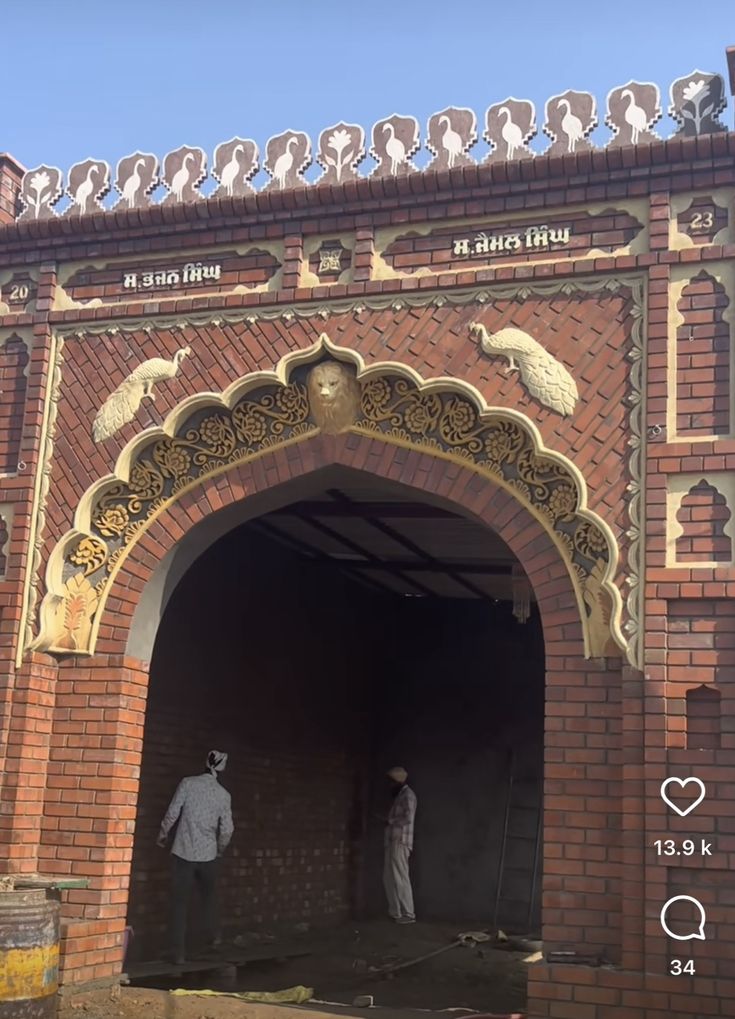 two men are standing in the doorway of an old brick building with ornate carvings on it