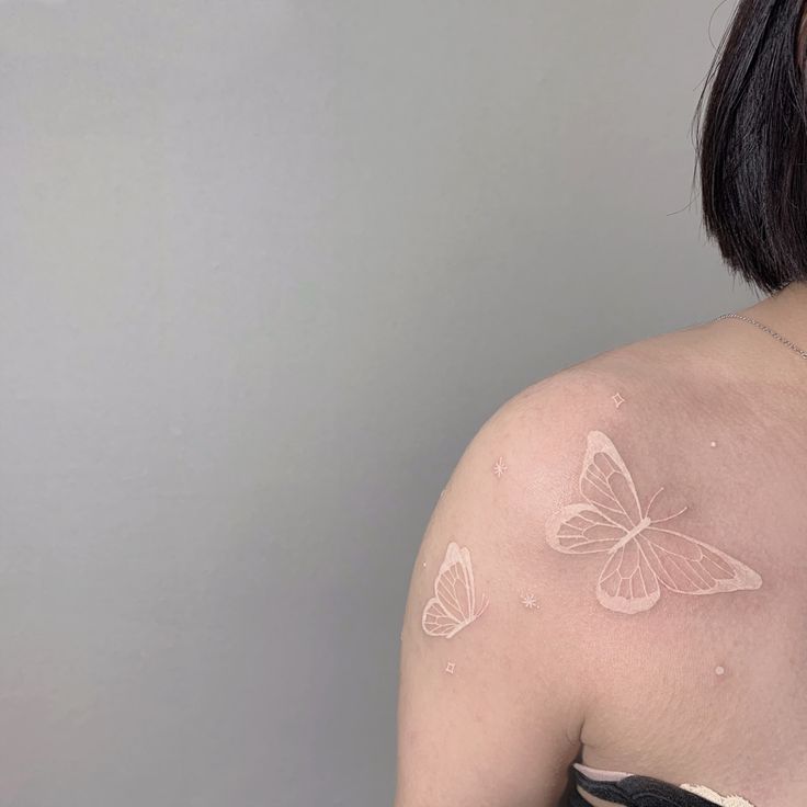 a woman with white butterflies on her back shoulder