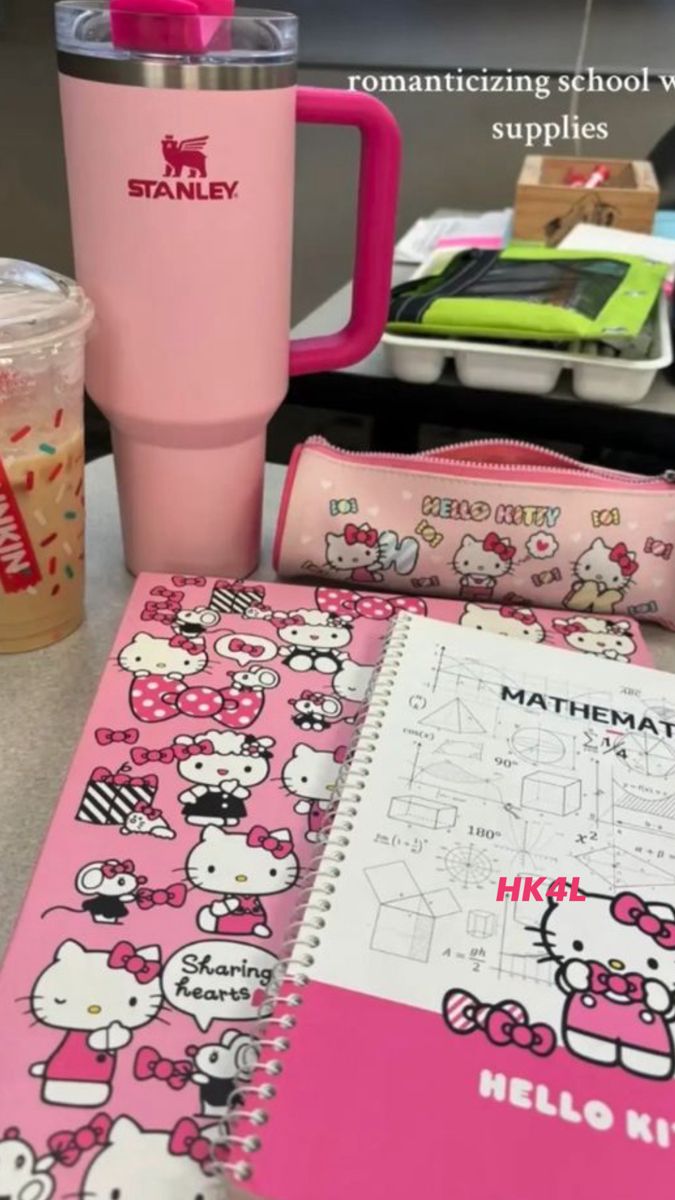 a pink hello kitty notebook and cup on a table