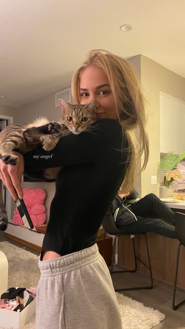 a woman holding a cat in her arms while taking a selfie with the camera