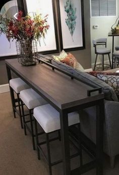 a living room filled with furniture next to a dining room table and bar stools