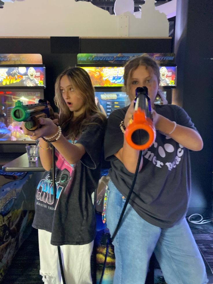 two people are playing video games in a room with arcade machines on the wall behind them