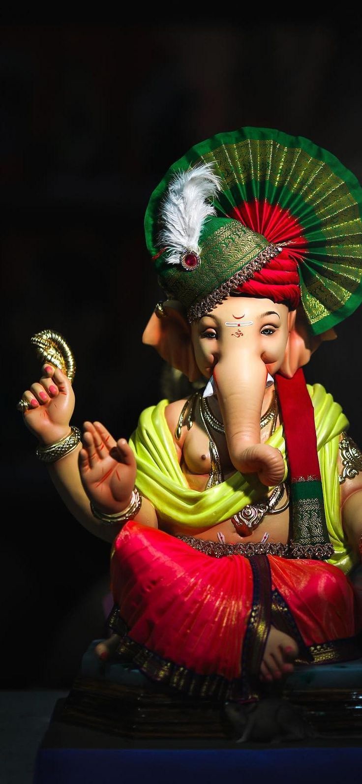 a statue of an elephant with a fan on it's head and two hands in the air