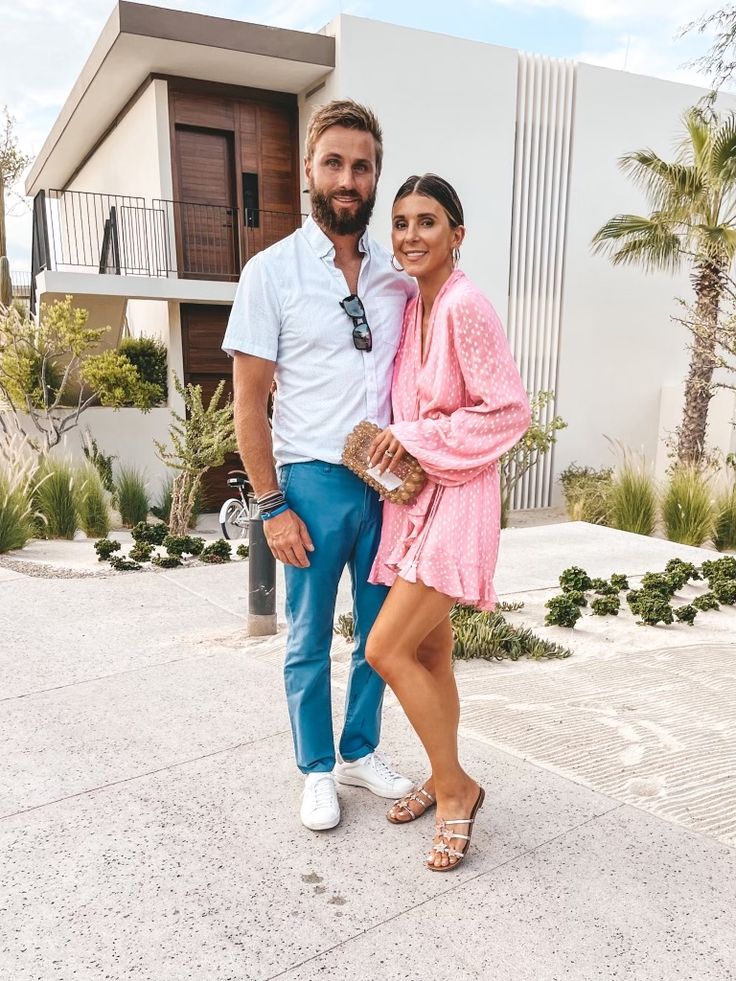 a man and woman standing next to each other in front of a building with palm trees