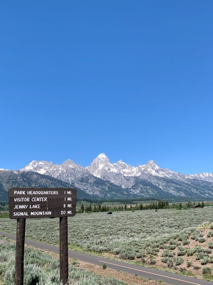 a sign on the side of a road with mountains in the background