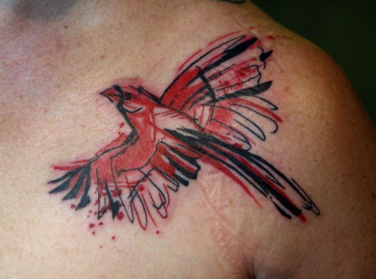 a red bird tattoo on the back of a man's upper arm and shoulder